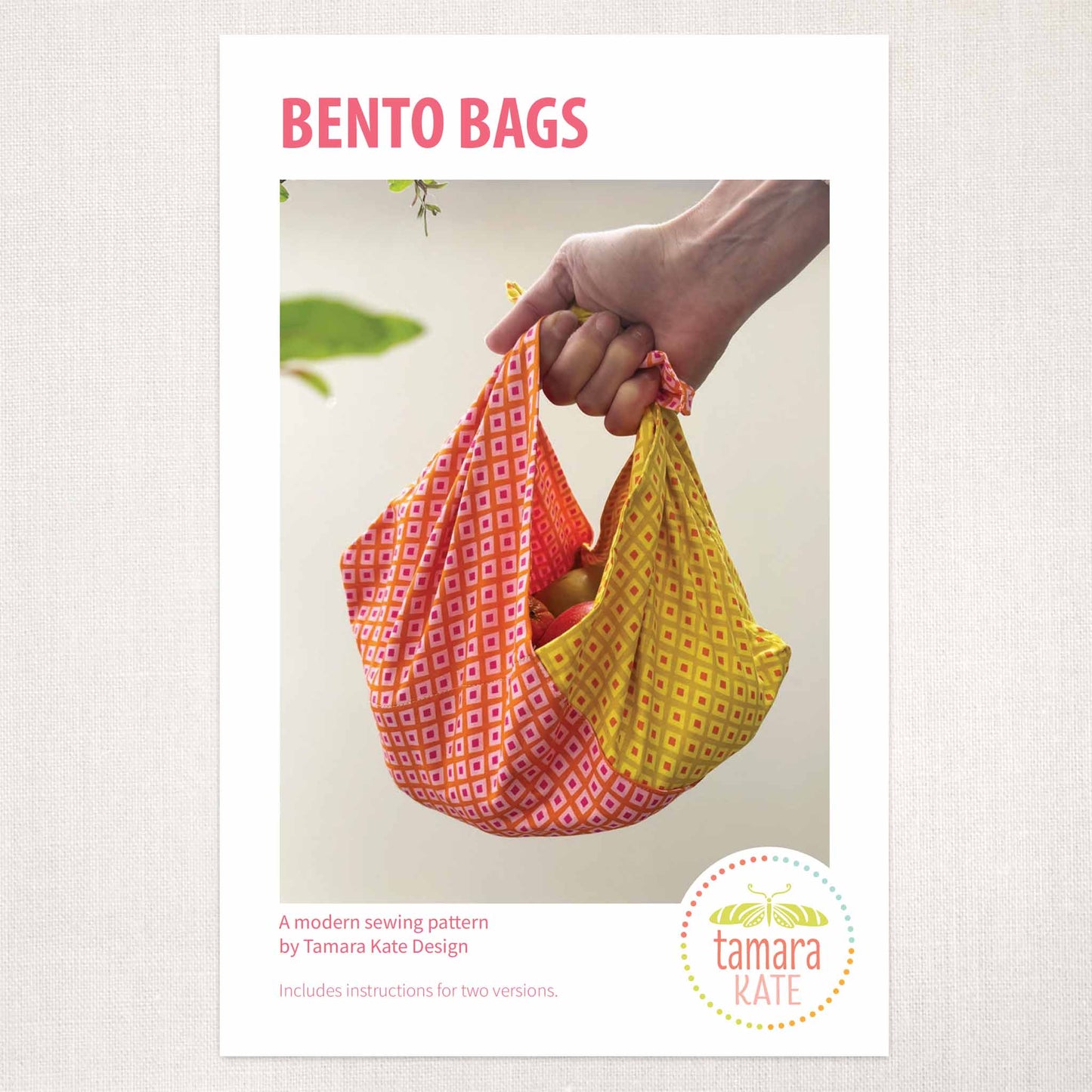 sewing pattern of a bright coral and yellow market bag carrying fruit, held in a hand