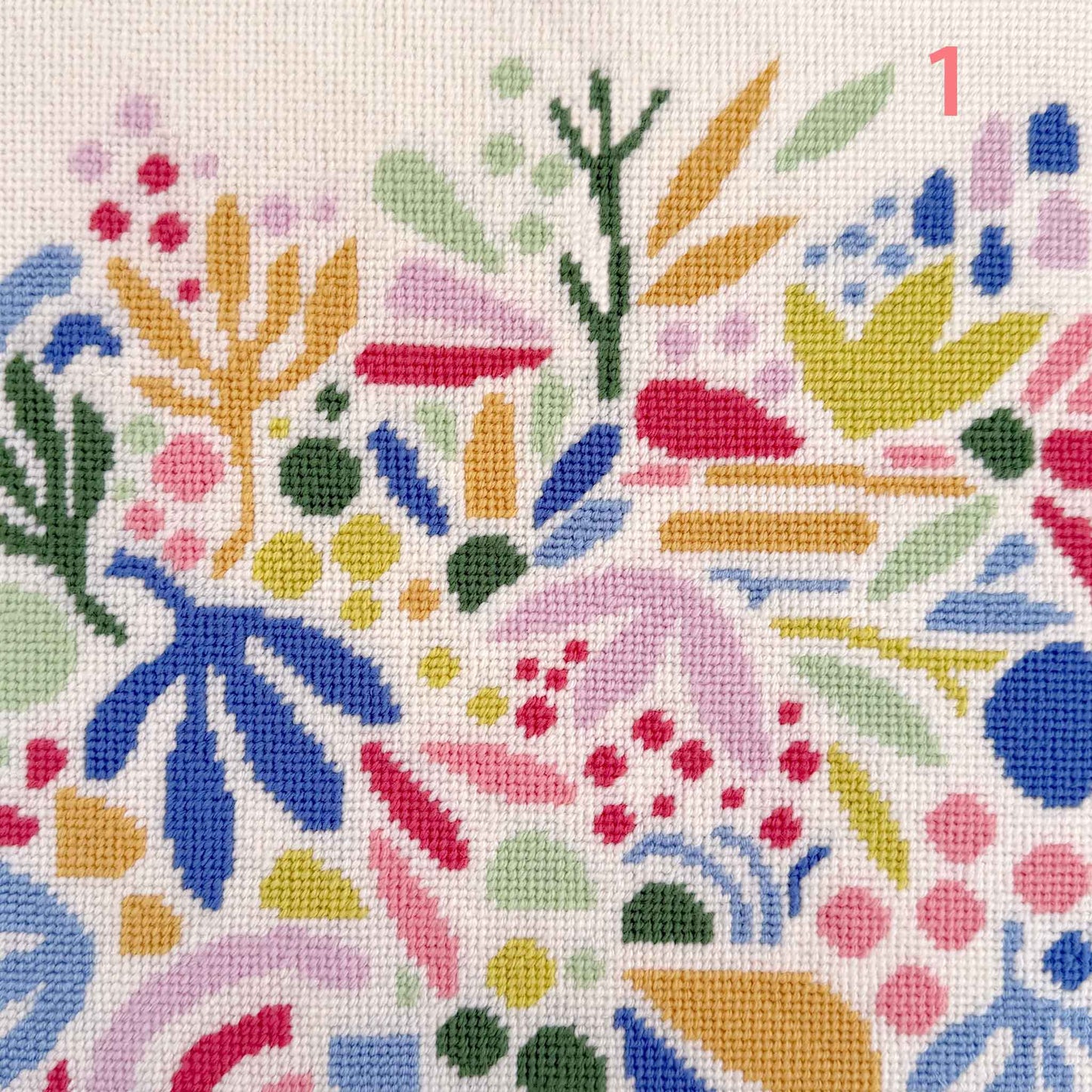 modern needlepoint of floating abstract leaves and shapes in blues, corals and greens on a cream ground
