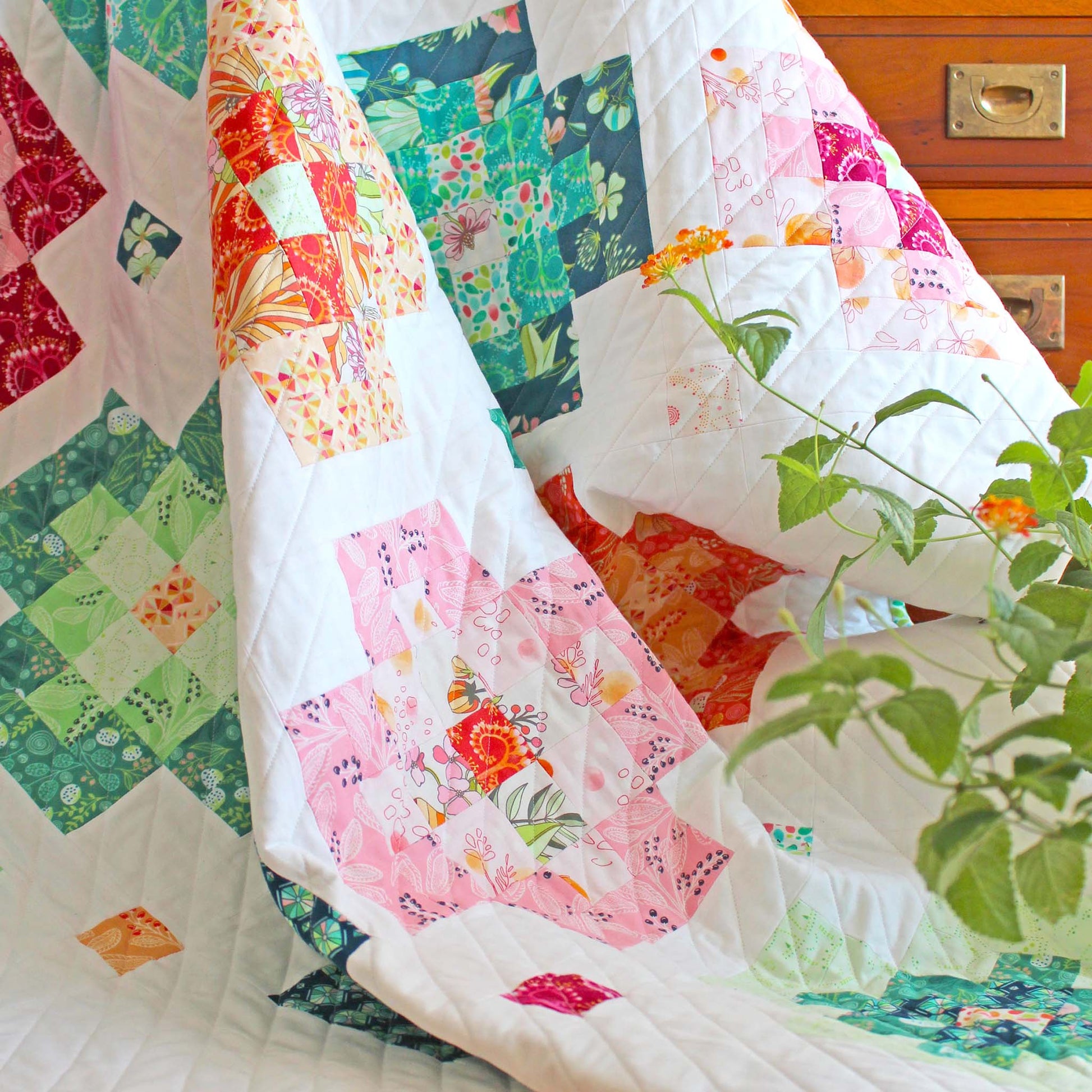 draped patchwork quilt in white, pinks and greens