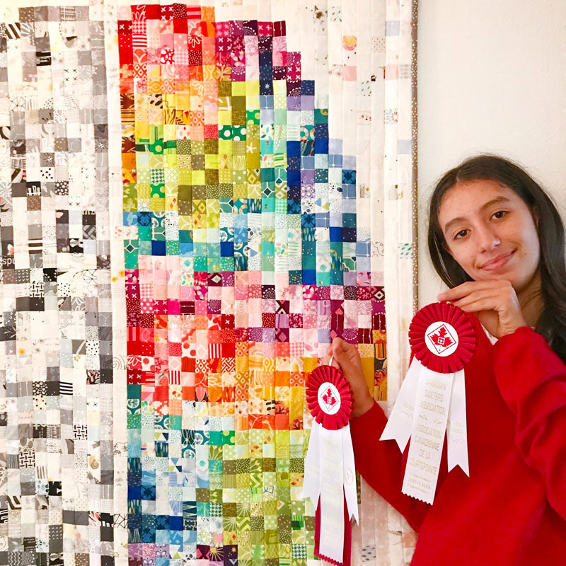 girl holding 2 ribbons in front of brain quilt