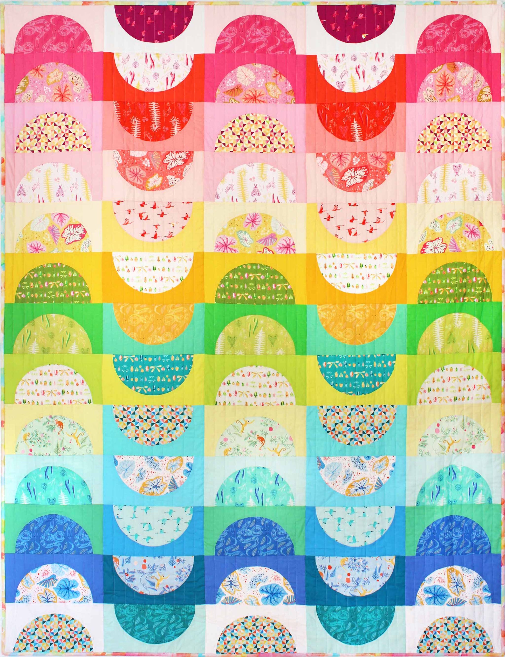 quilt of large half circles and arches arranged in rows in a rainbow of colours