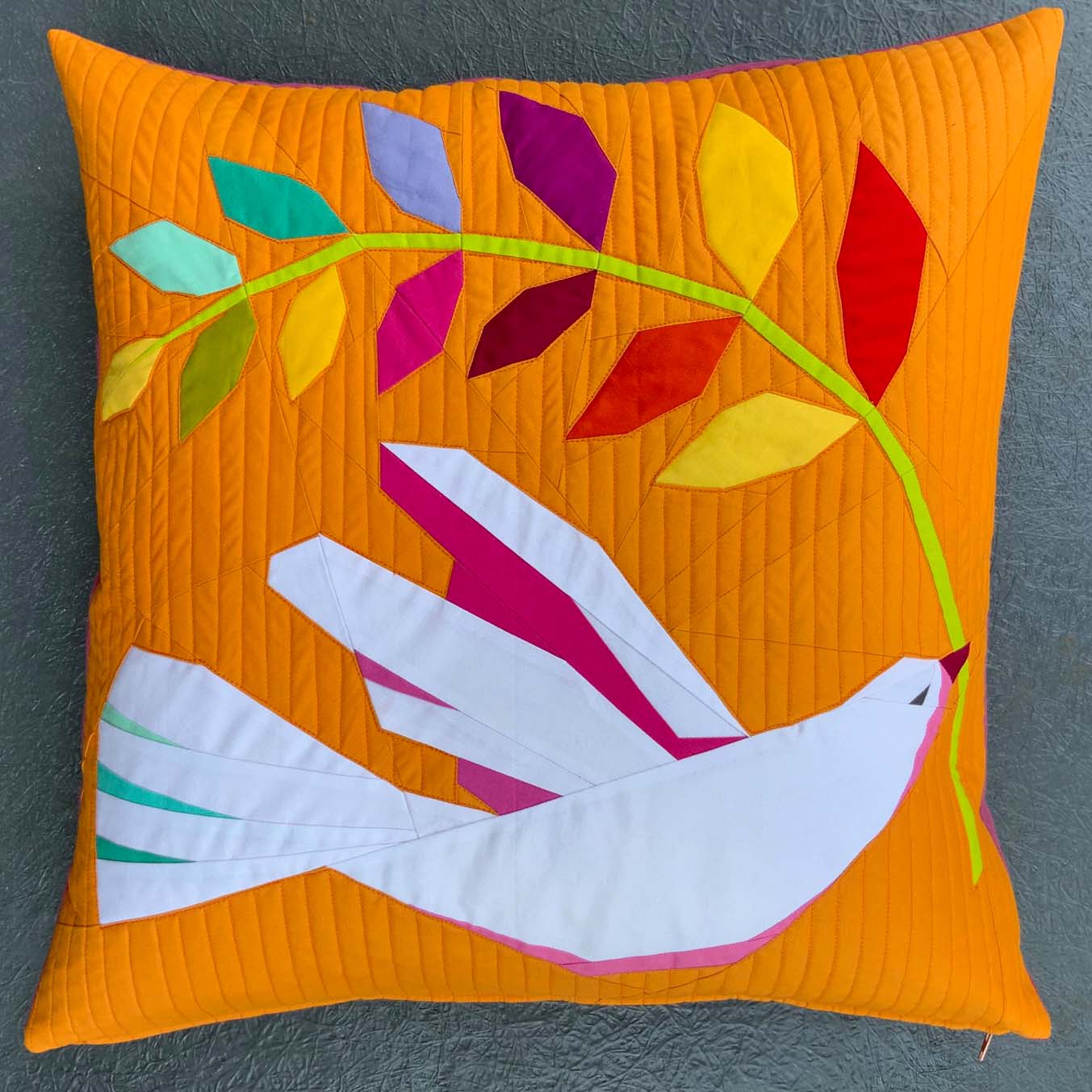 quilted throw pillow of a white dove holding a rainbow branch on an orange ground