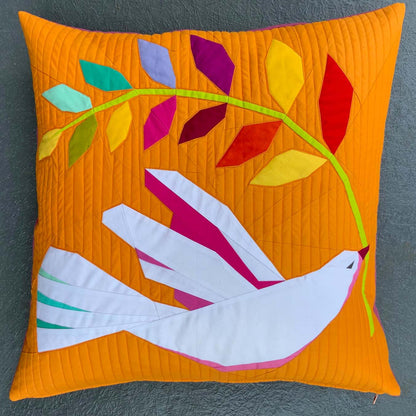 quilted throw pillow of a white dove holding a rainbow branch on an orange ground