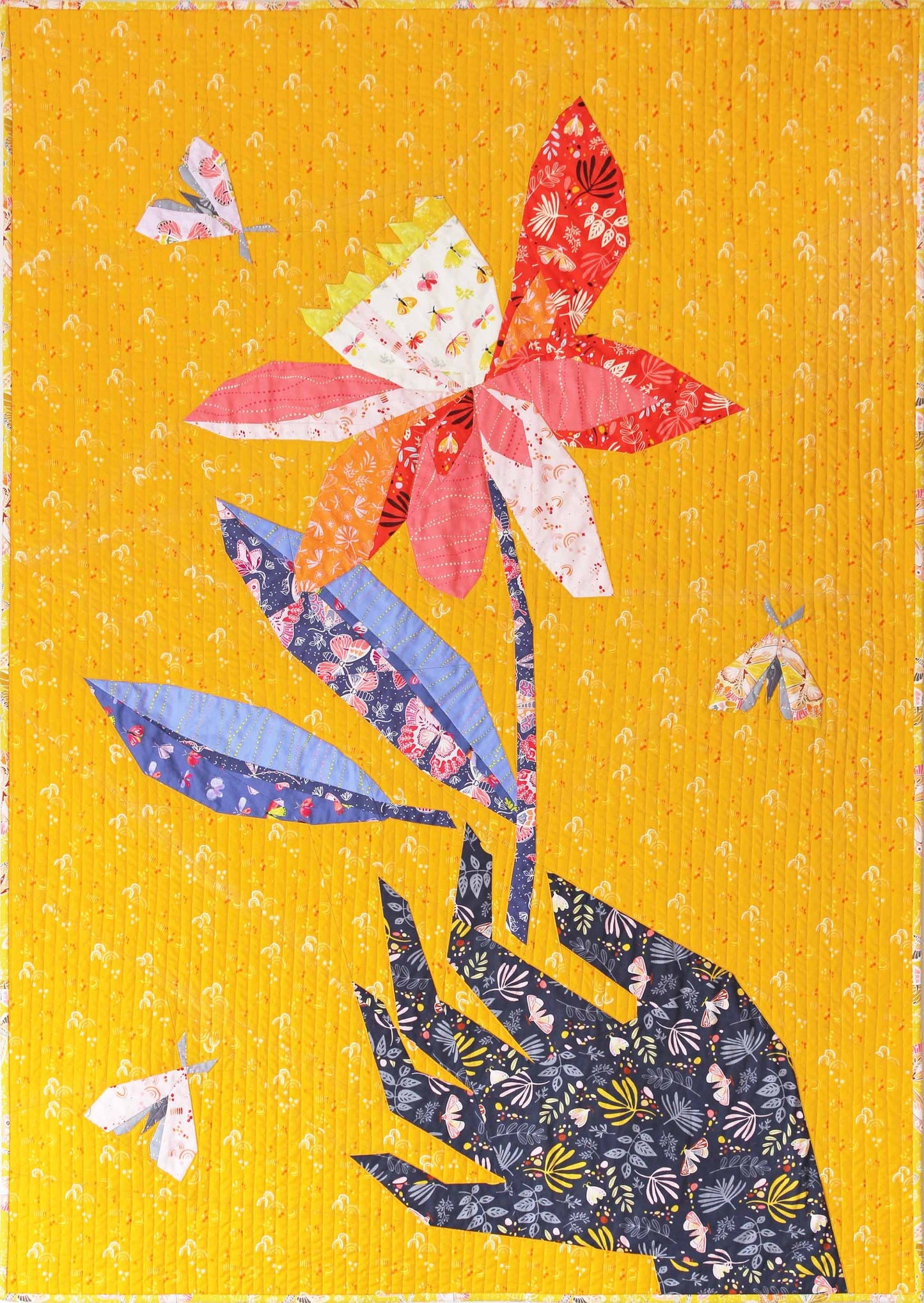 quilt of a large and holding a red and white flower on a yellow ground with small butterflies