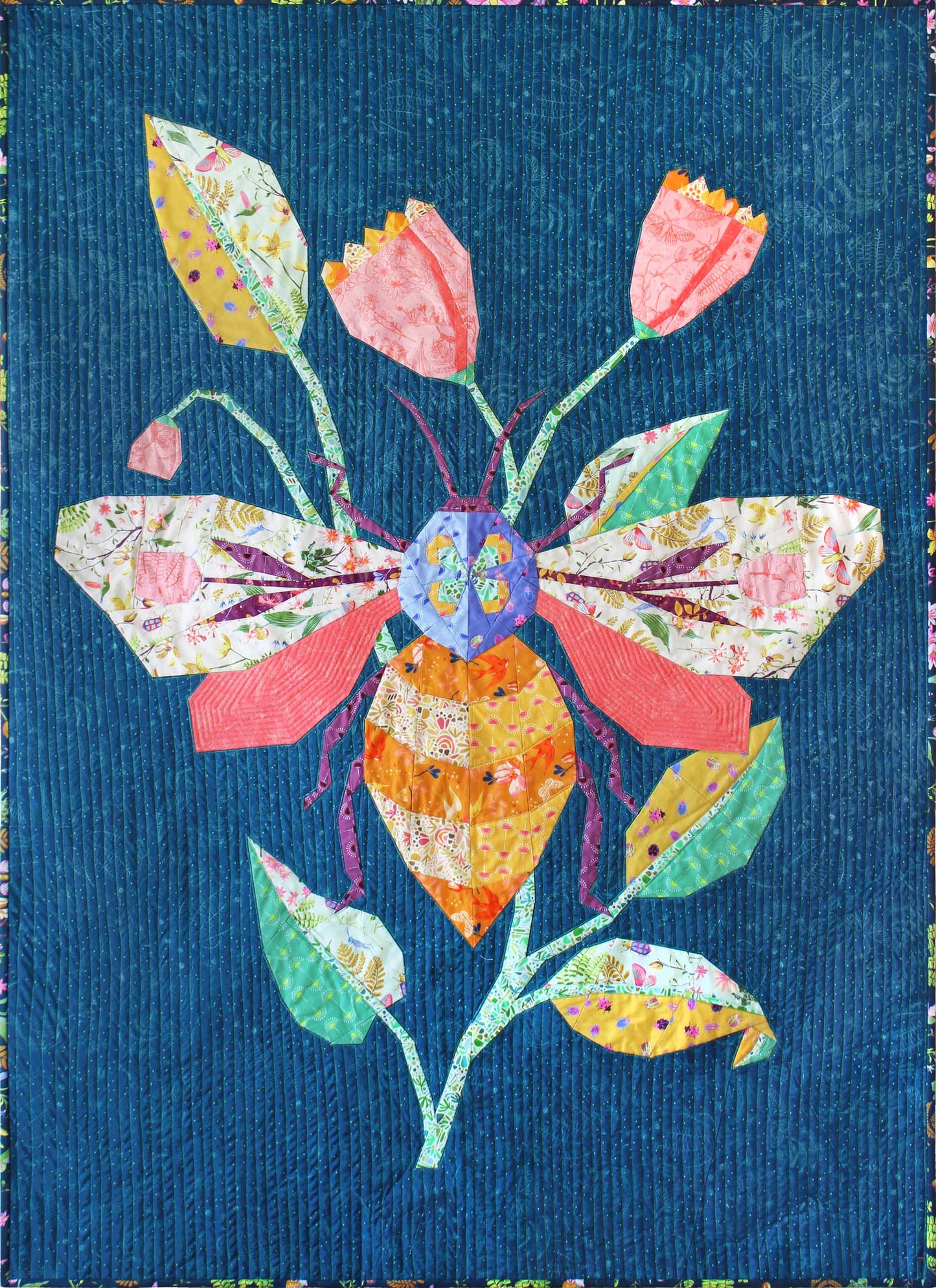 quilt of a large colourful bee with pink lowers and leaves on a dark teal ground